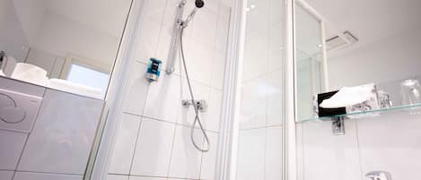 A modern bathroom with a glass-enclosed shower, a white sink, and a mirror above the sink.
