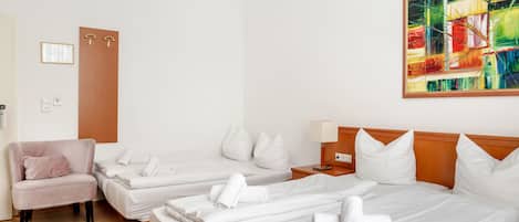 Une chambre d’hôtel avec deux lits, un canapé, une porte en bois, un tableau et une petite table avec une lampe.