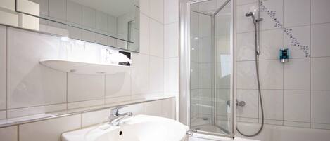A modern bathroom with a white sink, a glass shower enclosure, and a mirror above the sink.