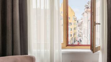 A room with a pink armchair, a glass table, and a window with a view of a cityscape.