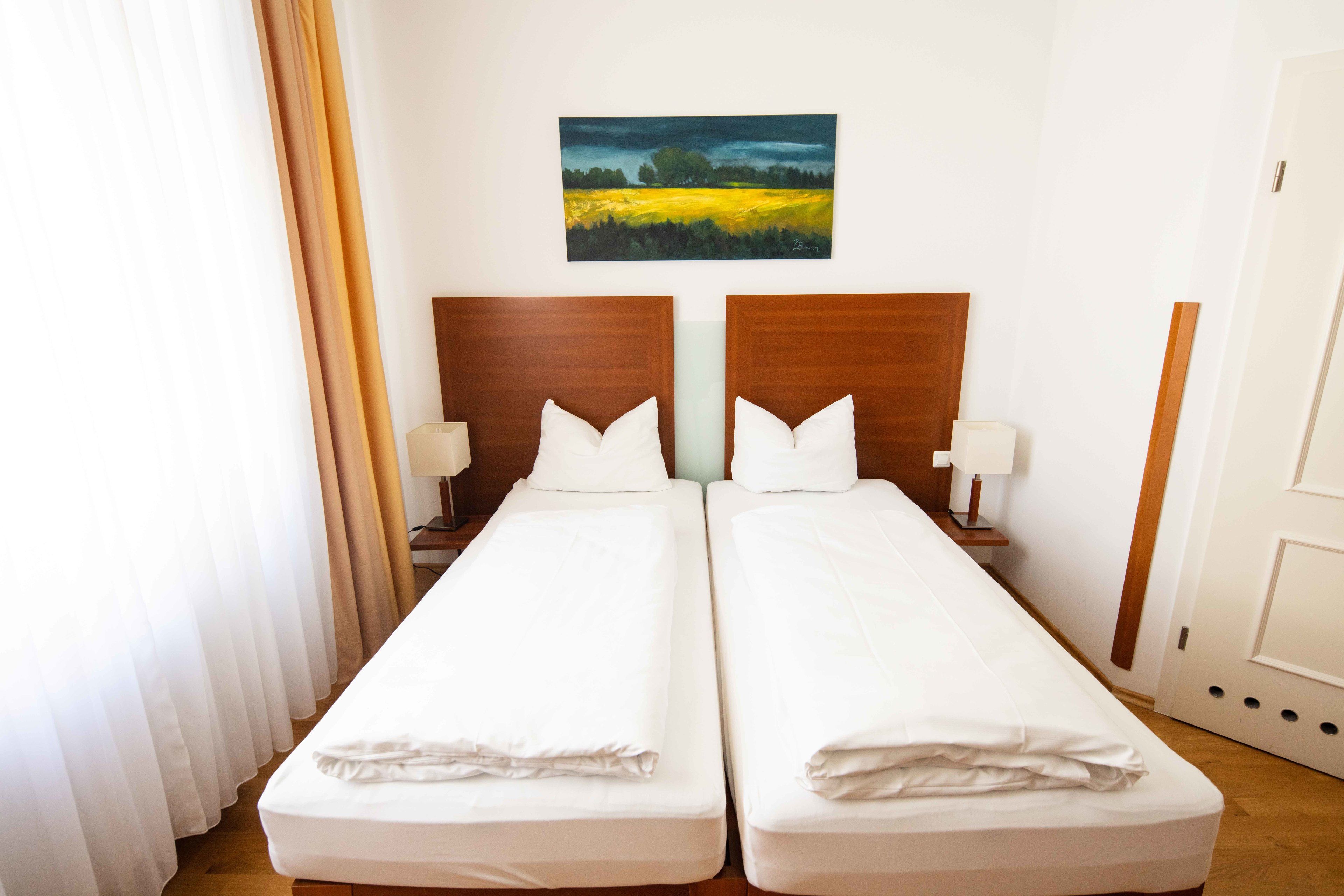 Un letto matrimoniale con lenzuola bianche, una testiera in legno e un comodino con una lampada.