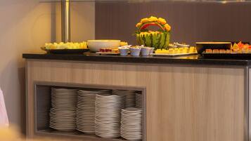 A buffet setup with various food items and a decorative watermelon centerpiece.