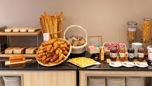A buffet with various breads, pastries, and condiments.