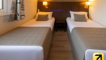 Een hotelkamer met twee bedden, elk met hoofdeinde, bedlampjes en een klein tafeltje ertussen.