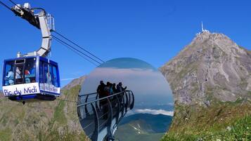 Une télécabine transportant des passagers, une montagne surmontée d’une tour et un paysage magnifique.