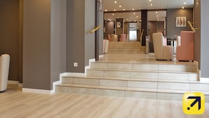 A hotel lobby with a staircase leading to a seating area.
