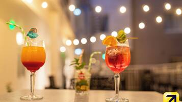 Two cocktails on a table with a blurred background of lights.