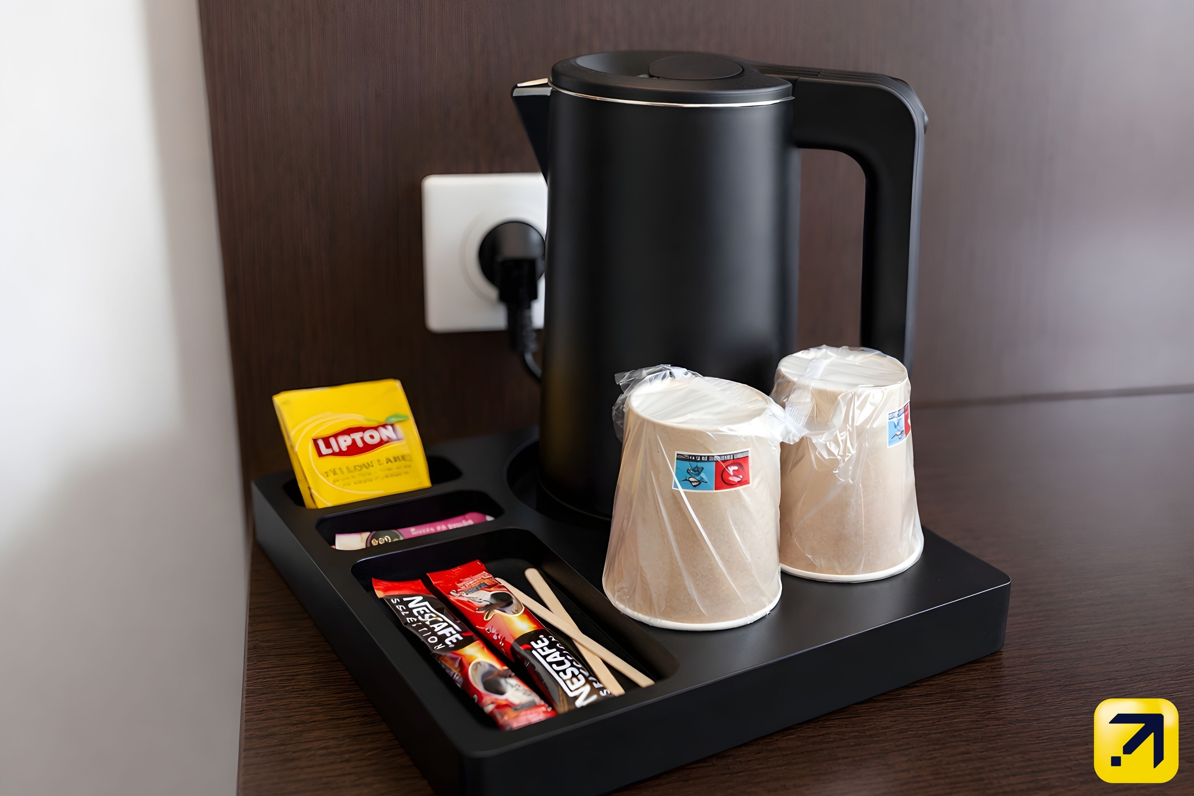 A coffee maker, two cups, a box of Lipton tea, and two packets of Nescafé instant coffee on a tray.