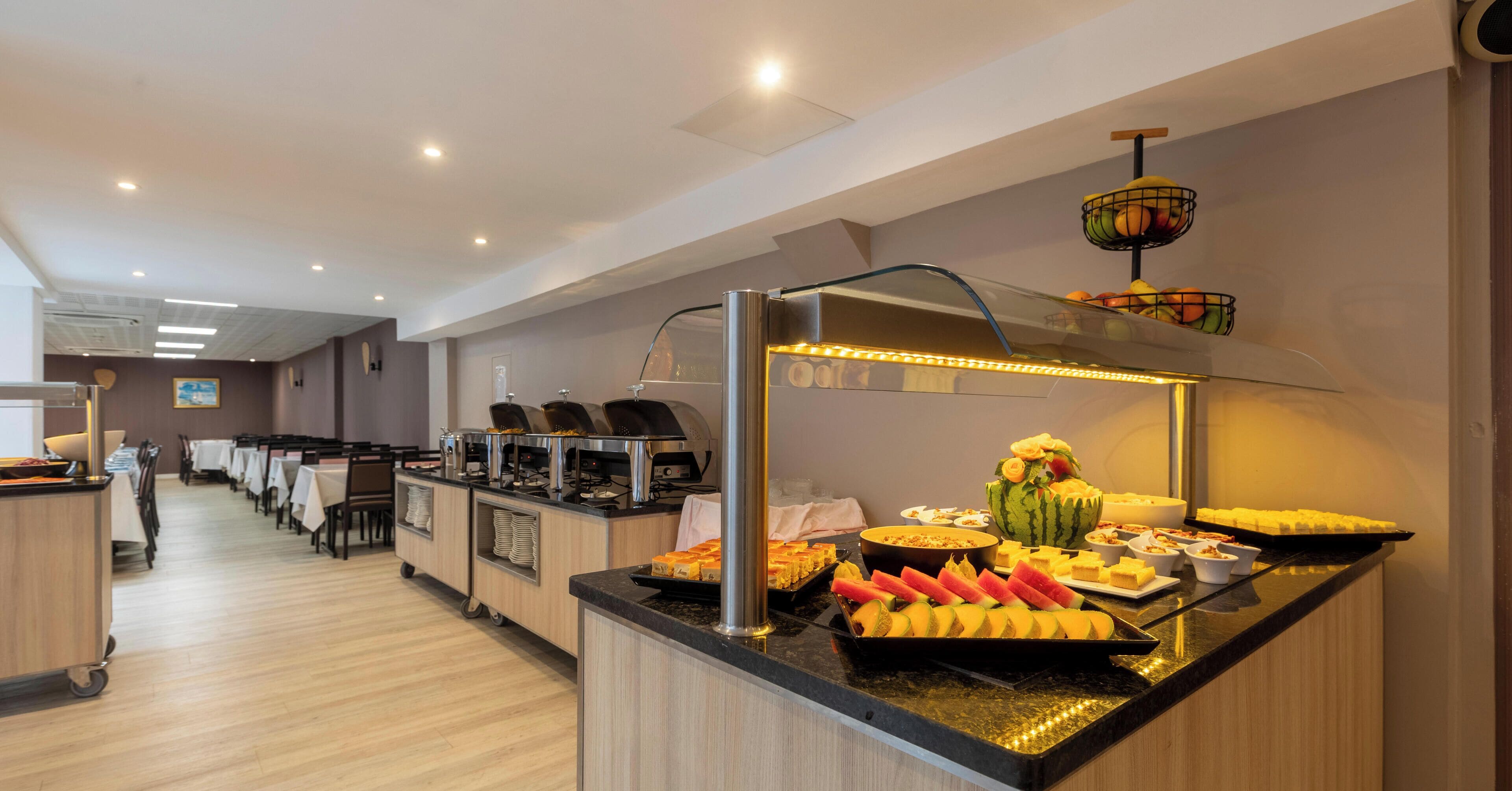 A buffet setup with various food items and a fruit display.