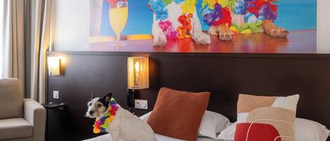 Ein Hotelzimmer mit Bett, Nachttisch, Lampe und einer Wand mit einem Poster.