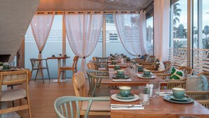 A restaurant with wooden tables and chairs, arranged in a spacious layout with large windows and sheer curtains. - The Original City, Hotel Cap Maya, Palais des congrès (Agde)