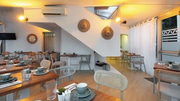 A restaurant with wooden tables, chairs, and a staircase leading to an upper level.