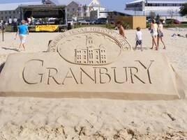 Una escultura de arena de Granbury, Texas, con un escenario y gente al fondo.