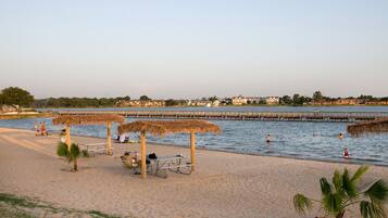 Enjoy a serene beach experience with a clear view of the water and a wooden pier.