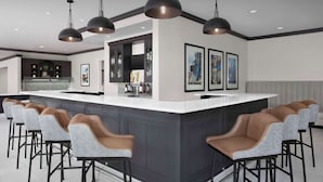 A modern kitchen with a central island, bar stools, pendant lighting, and framed artwork on the walls. - Hilton Garden Inn Granbury (Granbury)