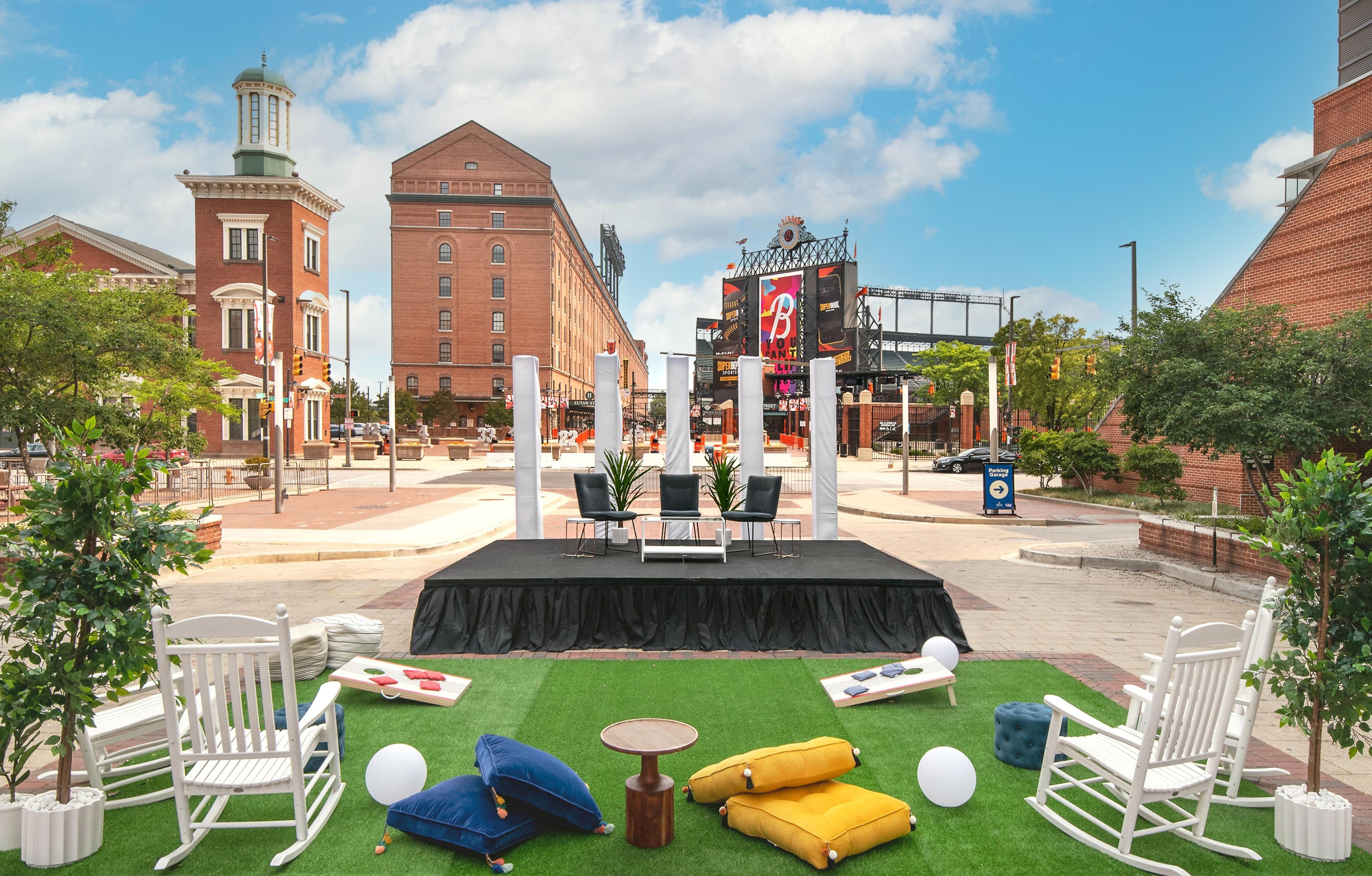 An outdoor seating area with chairs, a table, and cushions on artificial grass.