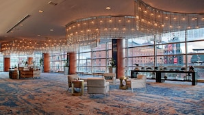 A spacious lobby with a large seating area, a bar, and a view of the cityscape through large windows. - Hilton Baltimore Inner Harbor (Baltimore)