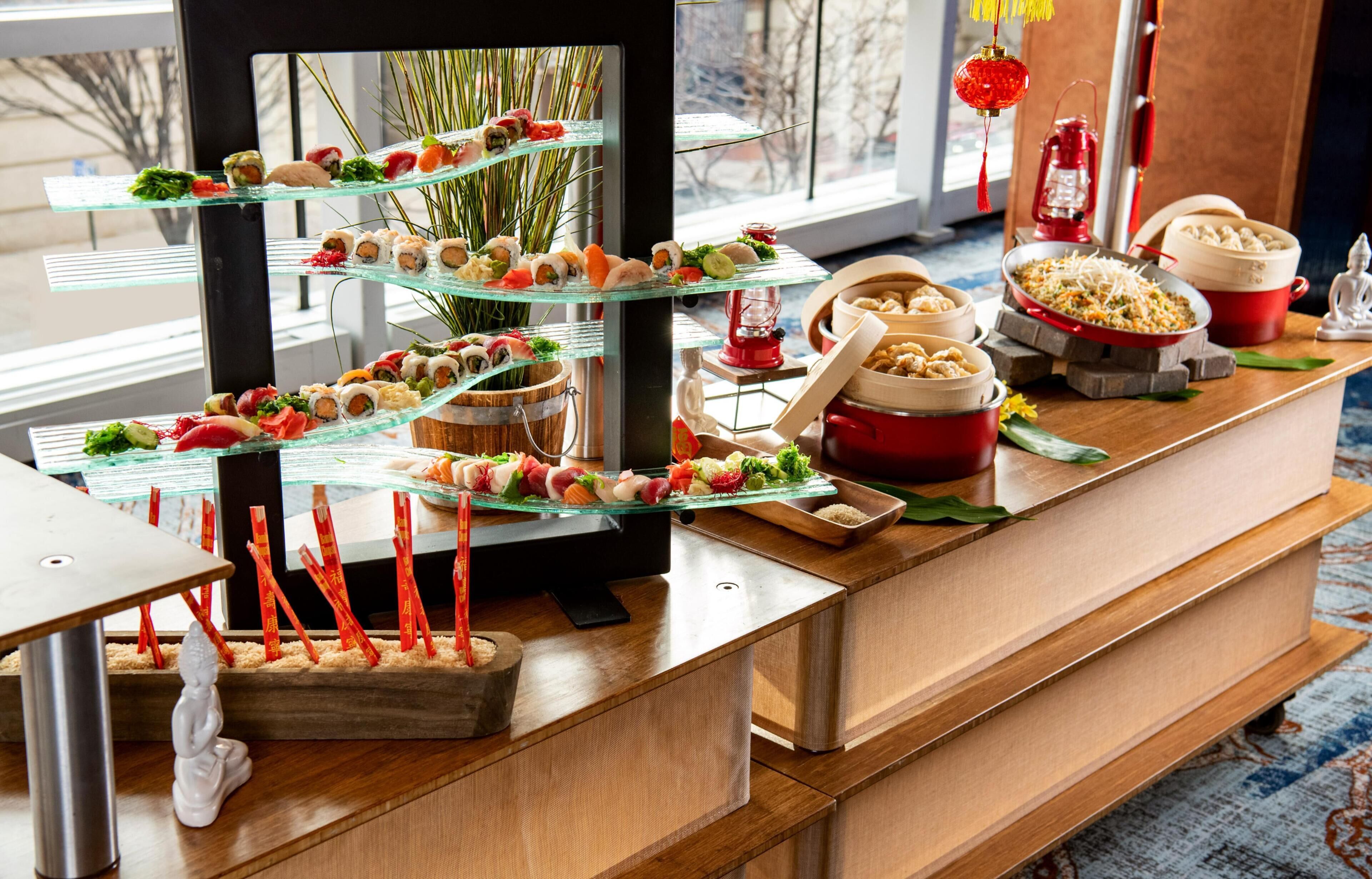 A buffet with various dishes, a Buddha statue, and traditional decorations.