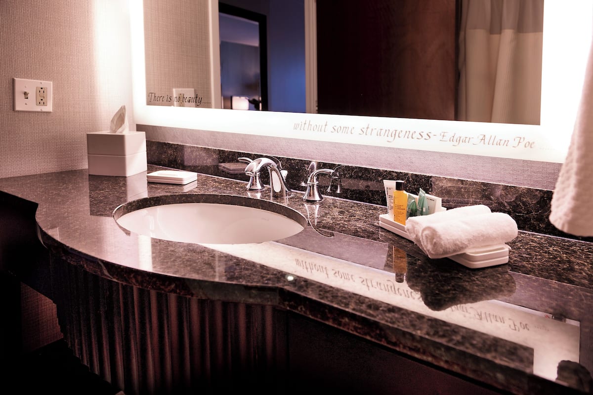 A modern bathroom with a large sink, a mirror, and a towel rack.
