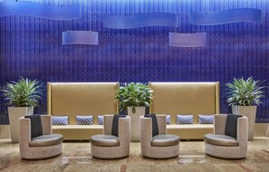 A lobby with a beige sofa, four armchairs, and potted plants. - Hilton Baltimore Inner Harbor (Baltimore)