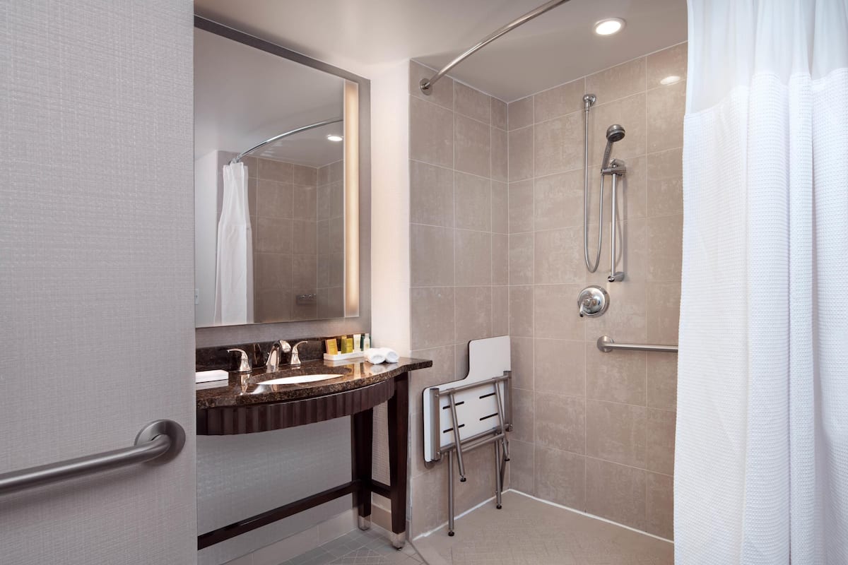 A modern bathroom with a shower, a vanity with a mirror, and a towel rack.
