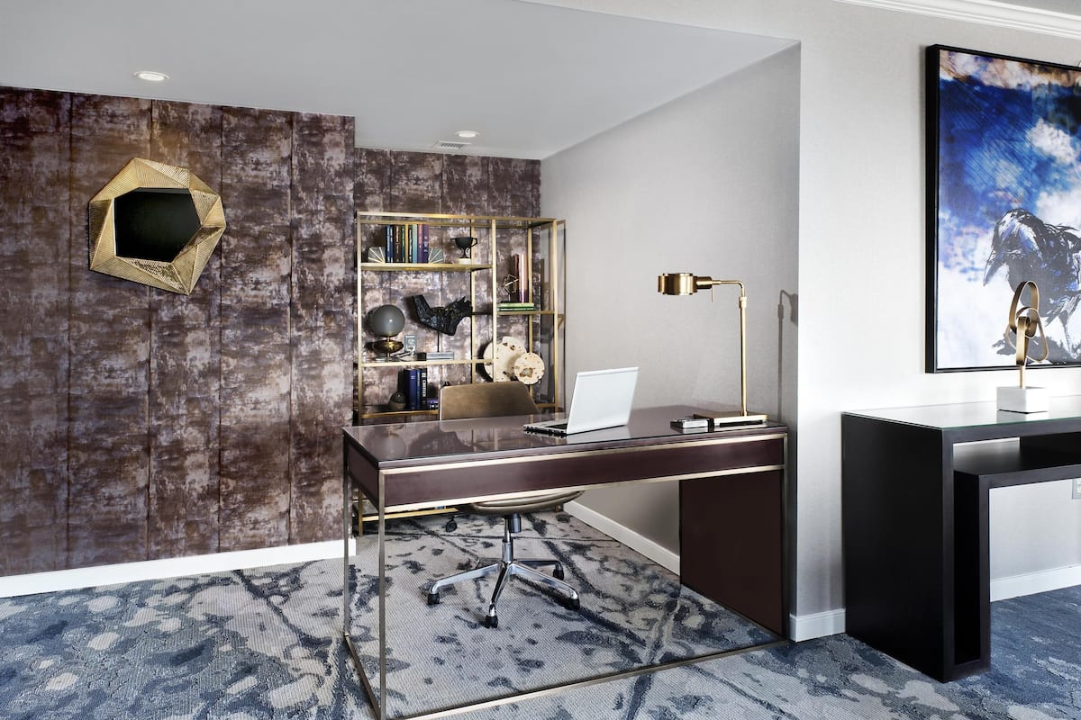 A modern office with a desk, chair, bookshelf, and a framed picture on the wall.