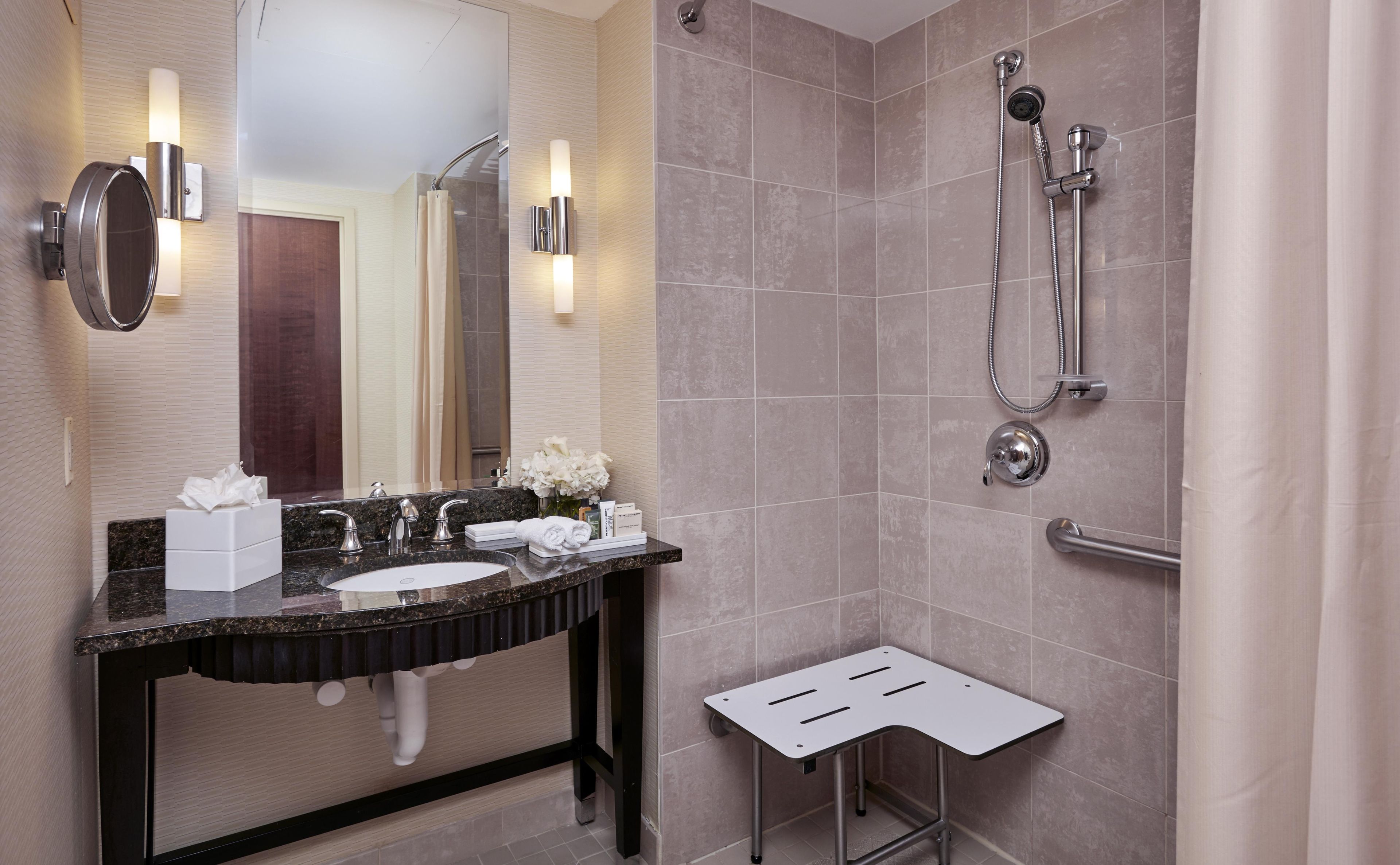 A modern bathroom with a sink, mirror, and shower.