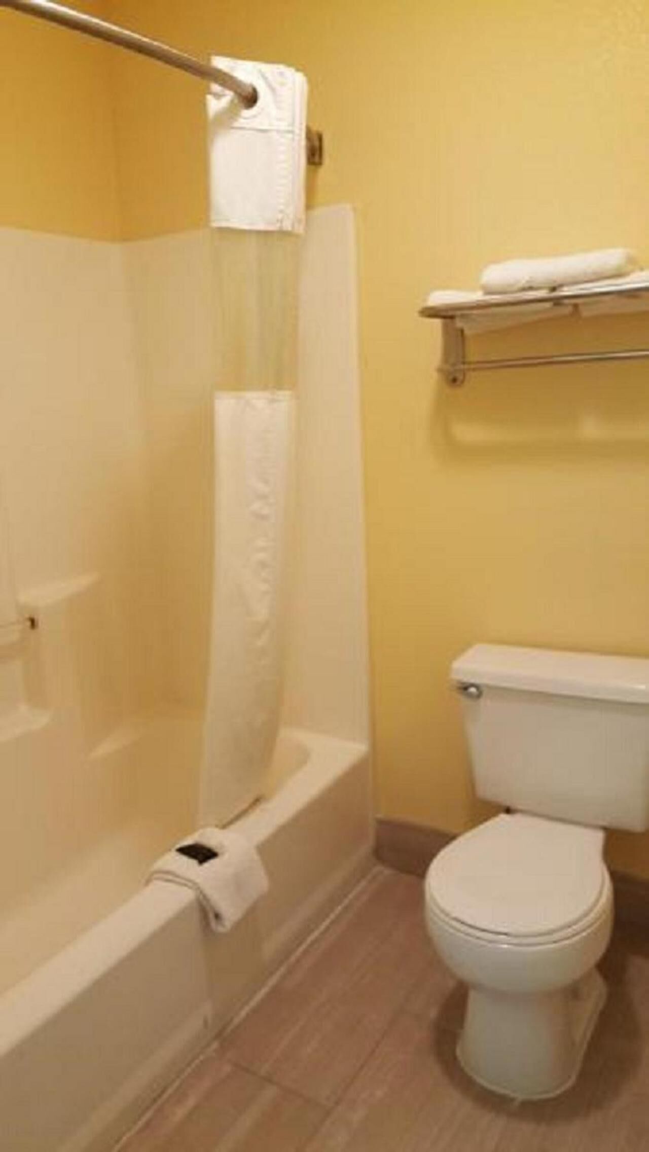 A bathroom with a bathtub, toilet, and a towel rack.