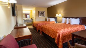 A hotel room with two beds, a desk, a chair, a lamp, and a painting on the wall.