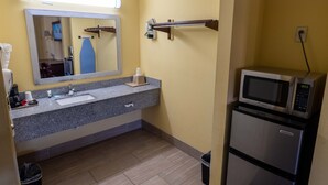 A bathroom with a sink, mirror, towel rack, and a microwave. - Loyalty Inn Hawkinsville (Hawkinsville)