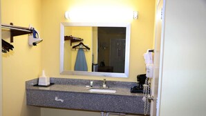 A bathroom with a granite countertop, a sink, a mirror, a towel rack, and a telephone.
