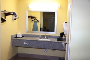 A bathroom with a granite countertop, a sink, a mirror, a towel rack, and a telephone.