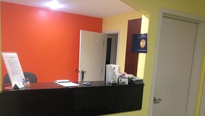 A reception desk with a black counter, a white door, and a sign indicating a 8.3 rating. - Loyalty Inn Hawkinsville (Hawkinsville)