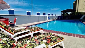 A swimming pool with lounge chairs and a covered seating area.