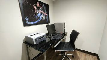 A home office setup with a desk, computer, printer, and a framed picture on the wall.