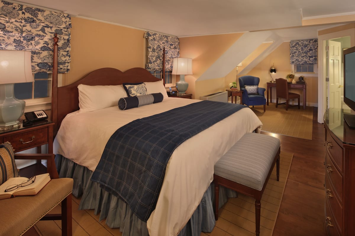 Une chambre d’hôtel avec un grand lit, un bureau avec une chaise, une télévision et un escalier menant à un étage supérieur.