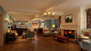 A spacious living room with a fireplace, comfortable seating, and elegant chandeliers. - Inn on Boltwood (Amherst)