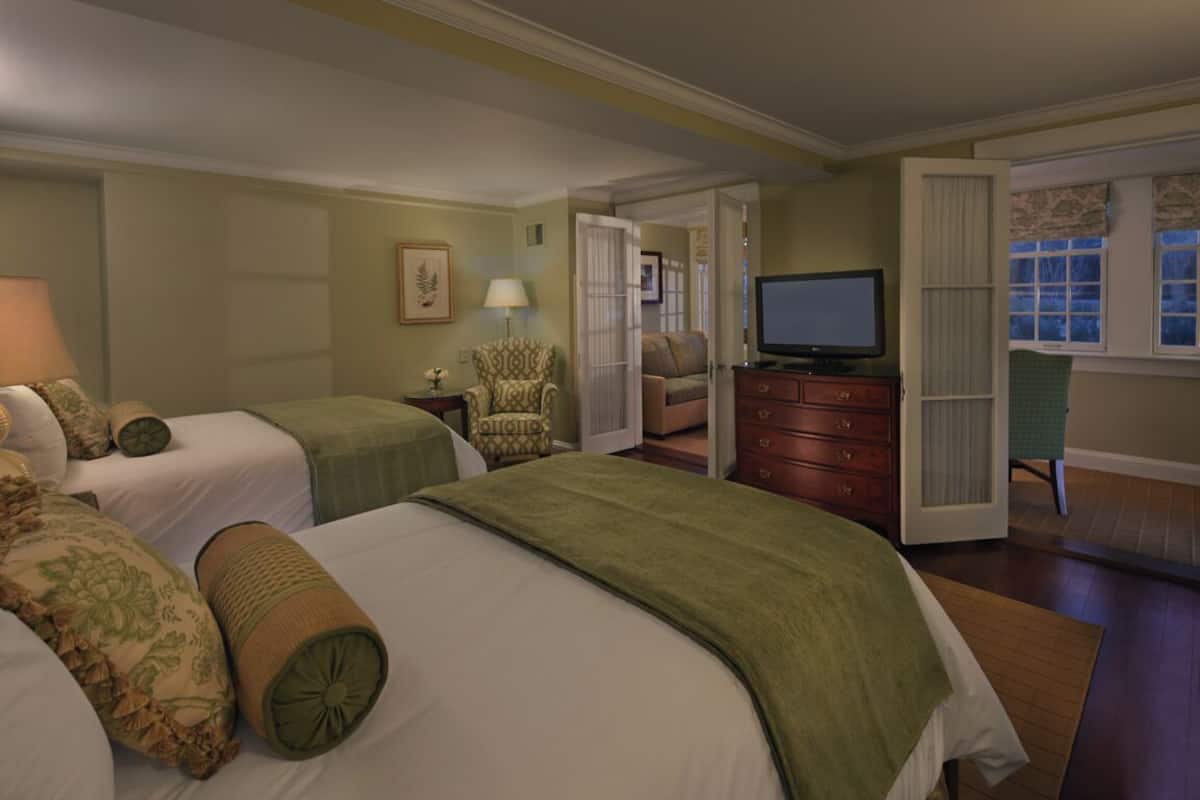 Une chambre d’hôtel avec deux lits, une télévision, un bureau et une chaise.