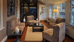 A modern living room with a sofa, armchairs, a coffee table, and a wine rack. - Inn on Boltwood (Amherst)