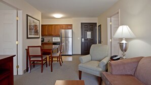 A compact living space with a dining area, kitchenette, and a seating area with a lamp. - Staybridge Suites Palmdale by IHG (Palmdale)