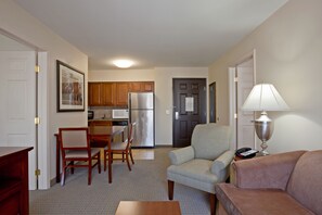 A compact living space with a dining area, kitchenette, and a seating area with a lamp. - Staybridge Suites Palmdale by IHG (Palmdale)