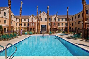 Un hotel con piscina, palmeras y un edificio de dos pisos.