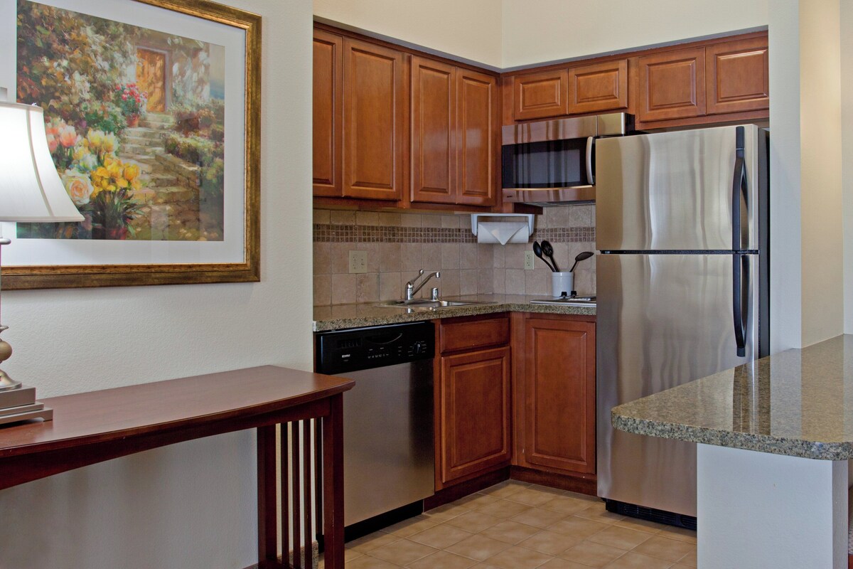 A kitchen with wooden cabinets, a stainless steel refrigerator, a dishwasher, and a microwave.