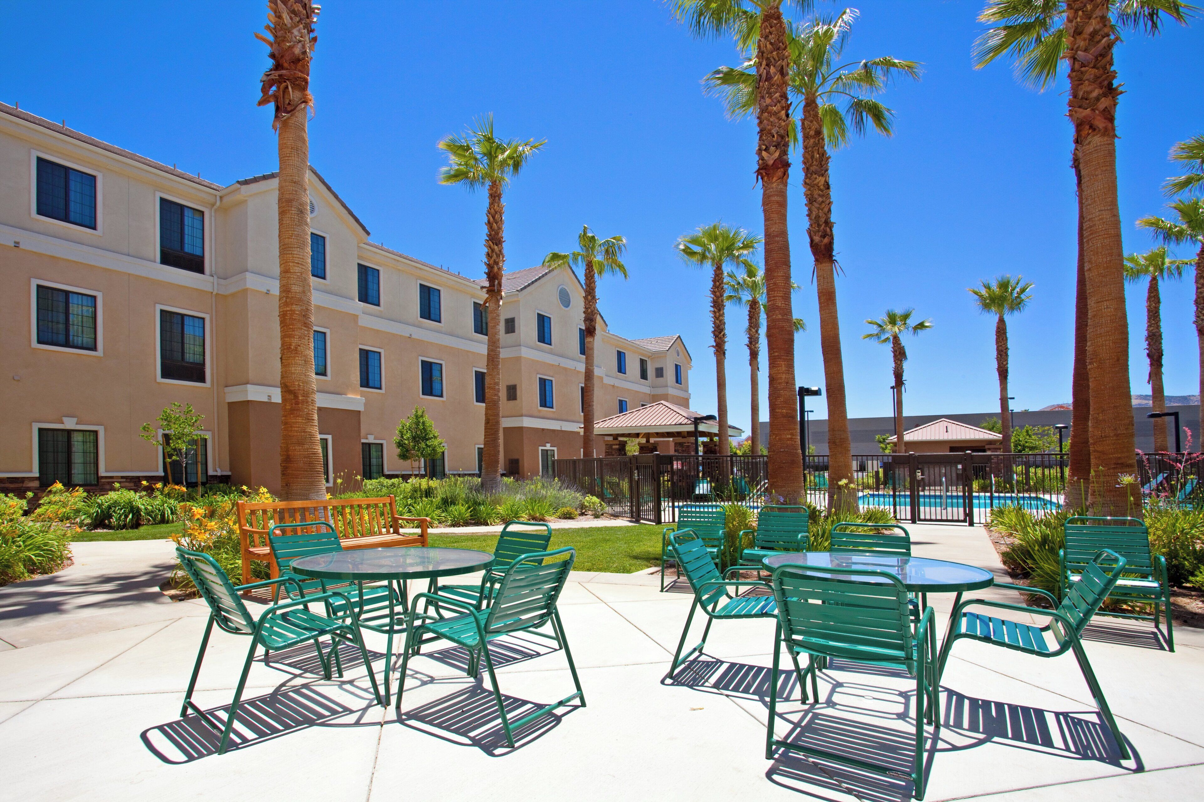 A hotel courtyard with outdoor seating and palm trees.
