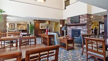 Un vestíbulo de hotel con chimenea, zona de comedor y mostrador de recepción.
