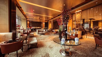 A spacious lobby with a central glass table, leather seating, and a decorative vase.