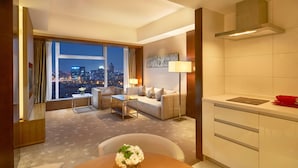 A hotel room with a city view, a sofa, a dining table with a vase of flowers, a lamp, and a kitchenette. - DoubleTree by Hilton Beijing (Beijing)
