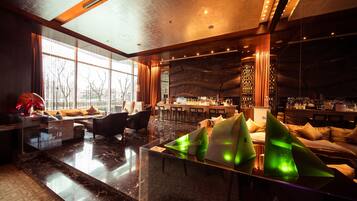 A modern hotel lobby with a bar area, seating arrangements, and large windows.