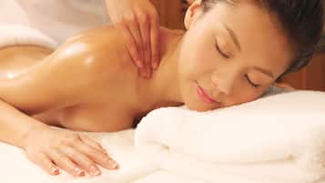 A person receiving a massage on a white towel-covered massage table.