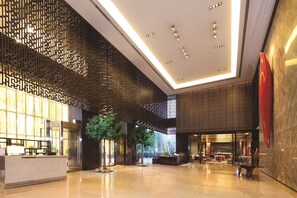 A spacious lobby with a reception desk, seating area, and a large red sculpture. - DoubleTree by Hilton Beijing (Beijing)